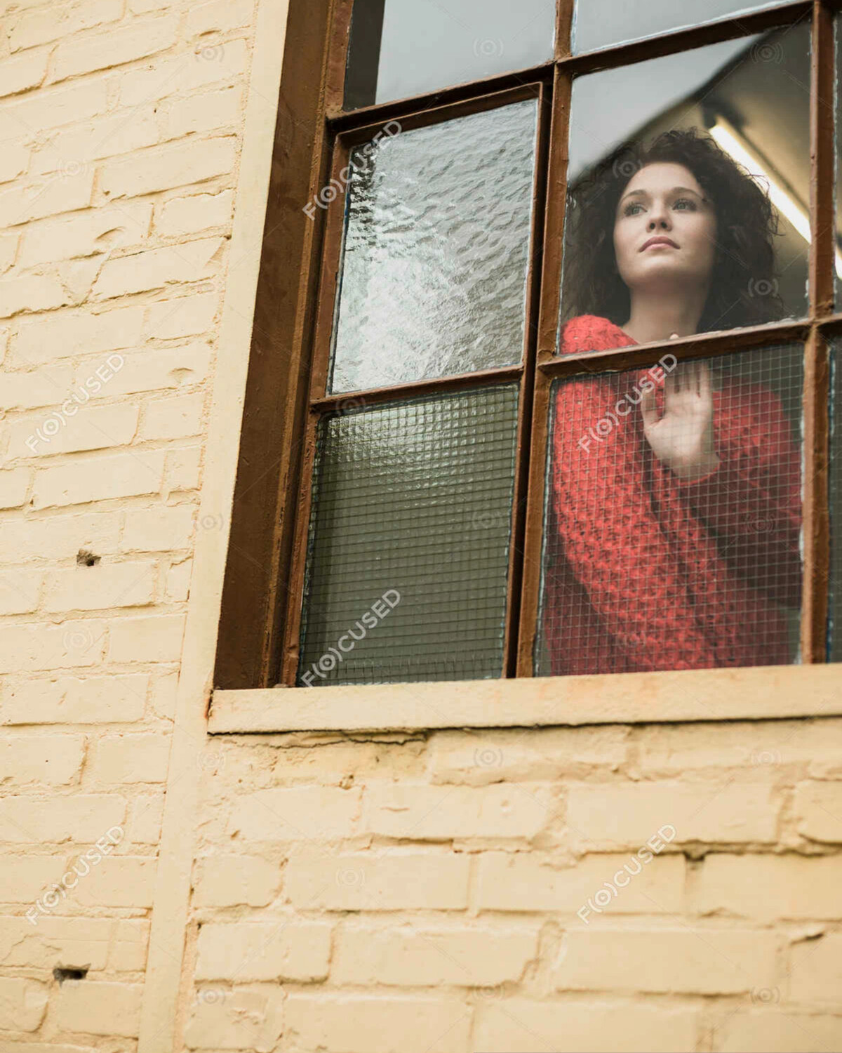 Девушка выглядывает из окна дома