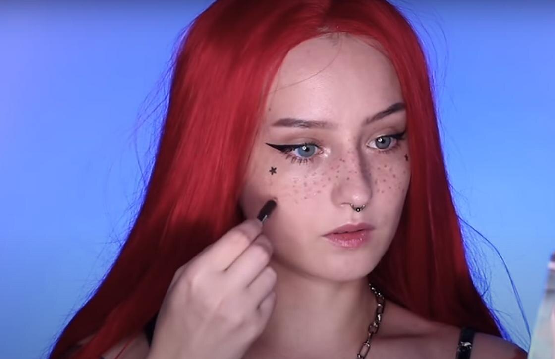    Девушка с красными волосами рисует веснушки карандашом:YouTube / momjesus