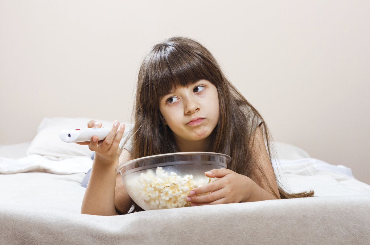 Everything is boring. Boring image. A girl eating Popcorn and watching TV.