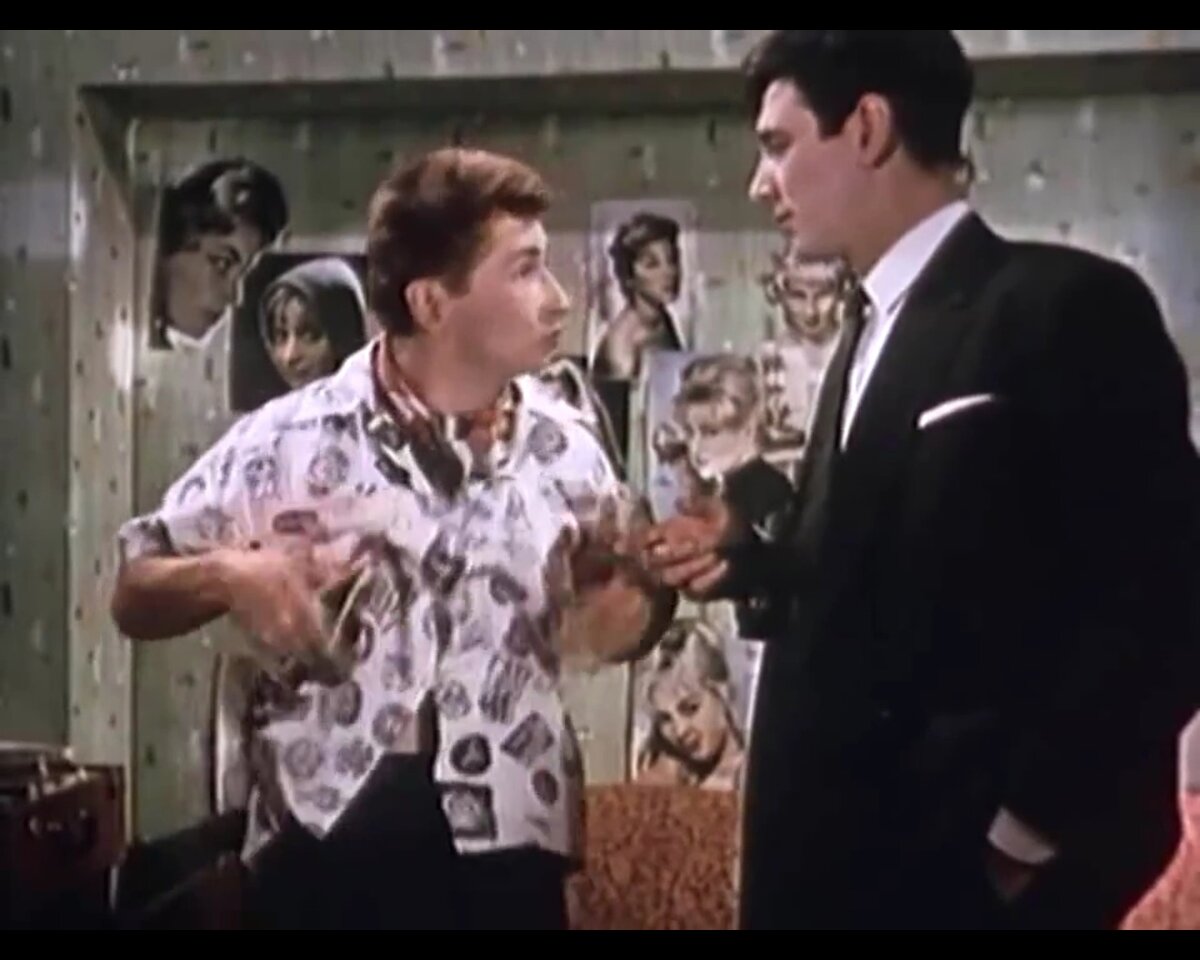 Таким незамысловатым движением главный герой показывает слово "шмотки"