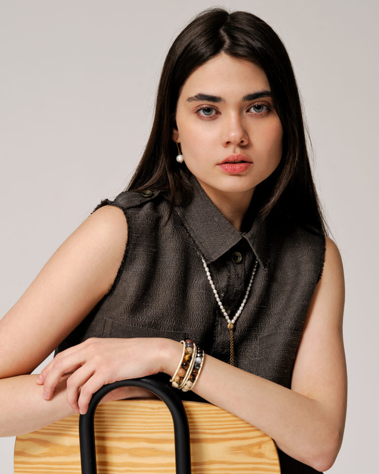 На модели бусы и серьги с жемчугом, браслет Чан Лу с яшмой, тигровым глазом, гематитом и бычьим глазом