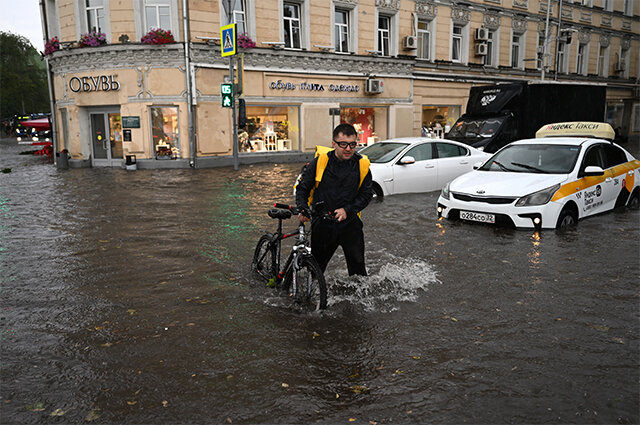    Мужчина с велосипедом на подтопленной улице в результате ливня в Москве. Фото:  РИА Новости/ Павел Бедняков