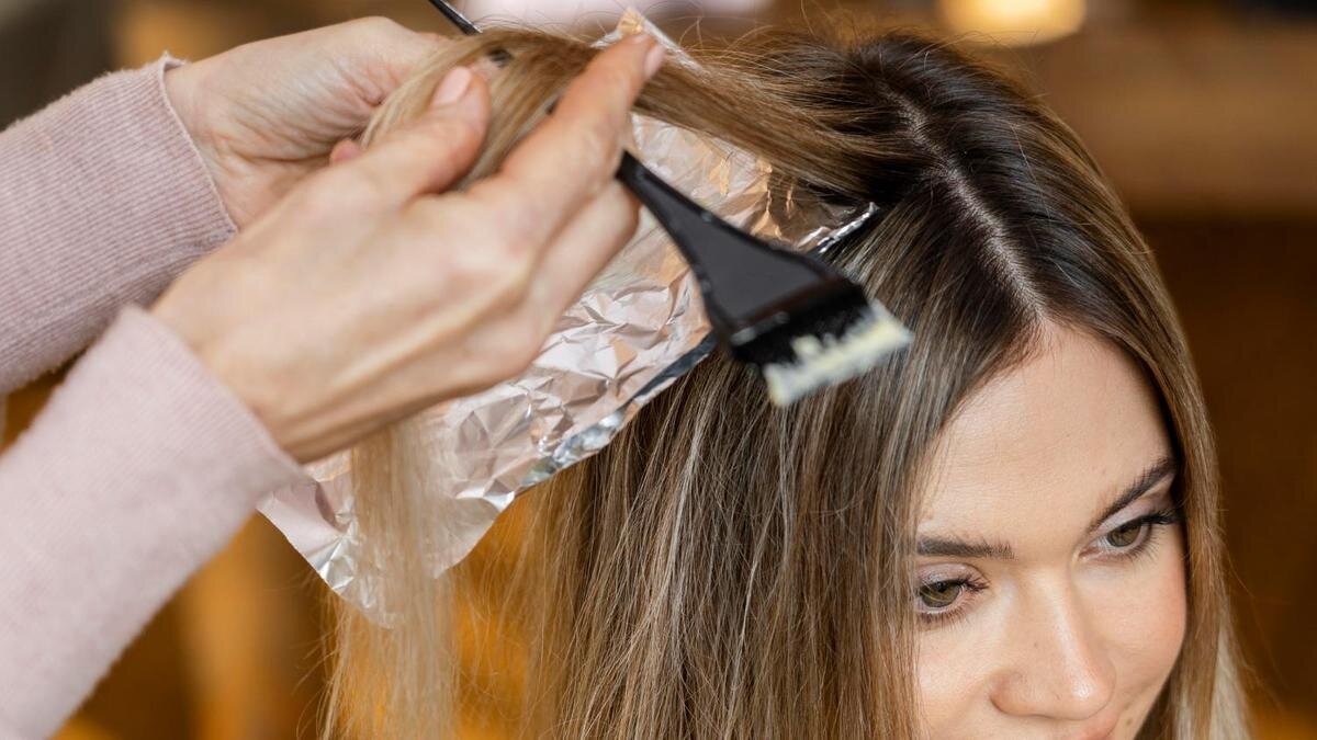    Девушке делают мелировмание, нанося краску щеткой на прядь волос:Freepik