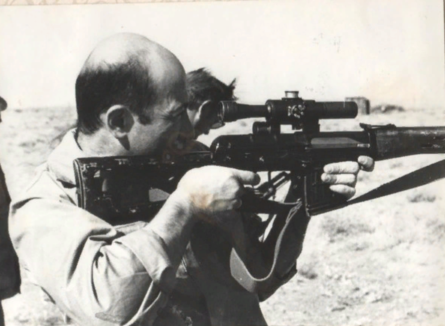 Александр Розенбаум смотрит в оптический прицел винтовки в Афганистане.