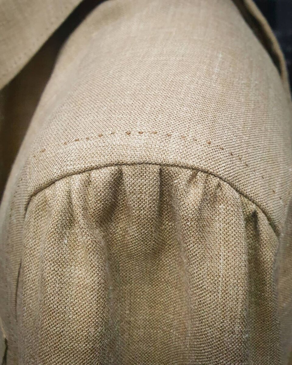 Верхняя рубашка в стиле сафари из смеси шерсти, шелка и льна от Caccioppoli в ателье Bourbaki. Коричневые роговые пуговицы и ручная вспушка в тон пуговиц прекрасно декорируют изделие.