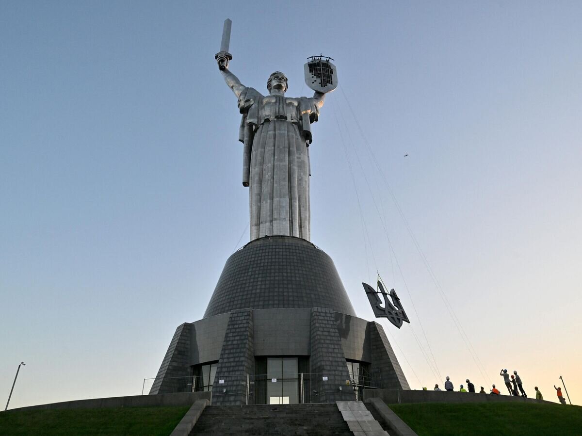    Рабочие устанавливают герб Украины на монумент "Родина-мать" в Киеве© AFP 2023 / SERGEI SUPINSKY