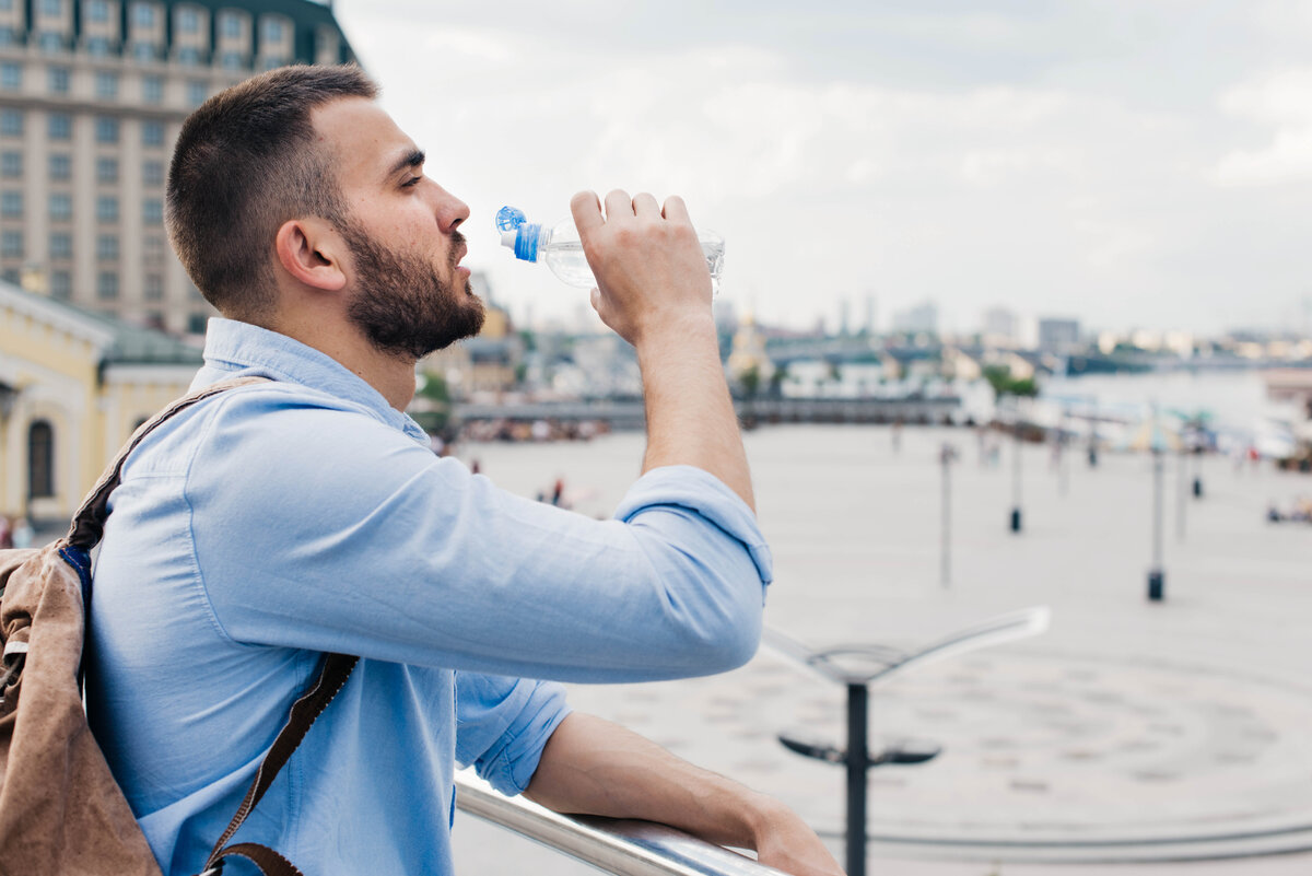 Drink travel. Путешественник с водой. Мужчина пьет воду. Человек хочет пить фото. Парень в наушниках пьют воду.