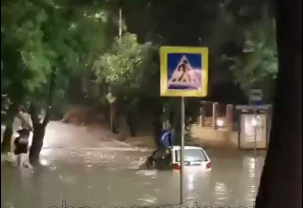    Водитель в Севастополе через окно выбирается из тонущей на улице машины. Фото: кадр видео/ ТГ-канал chp_sevastopol
