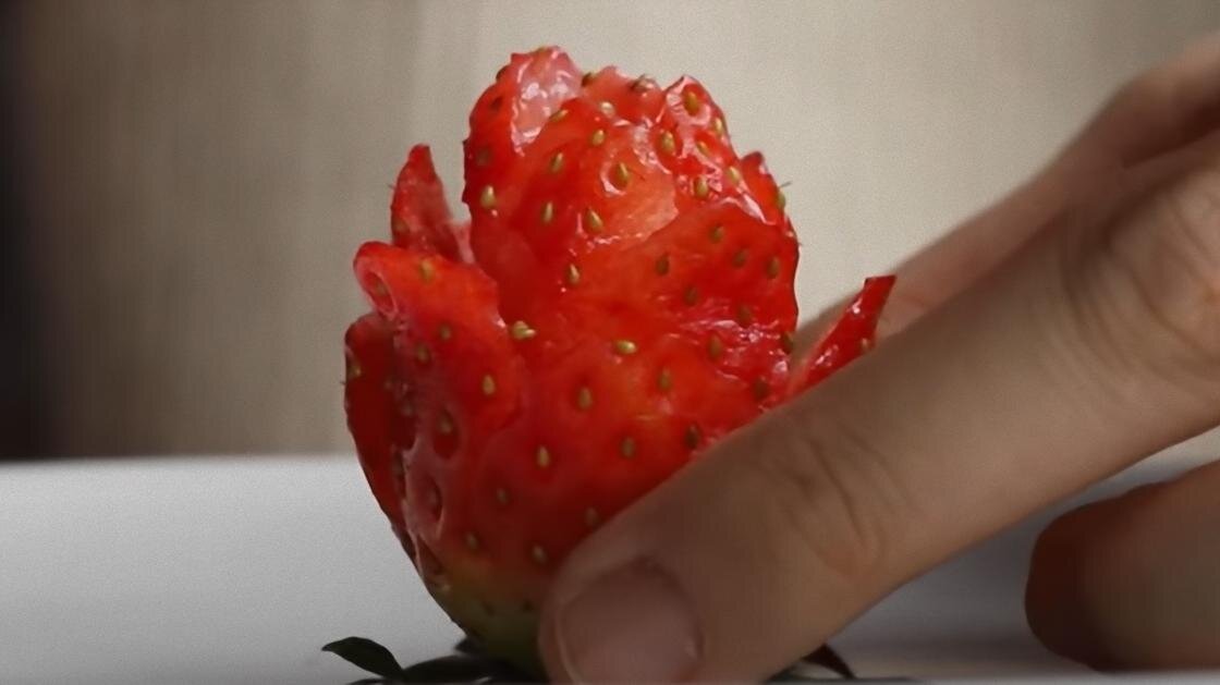    Пальцами придерживают клубнику, нарезанную в виде розы:YouTube / 우리의식탁 W TABLE