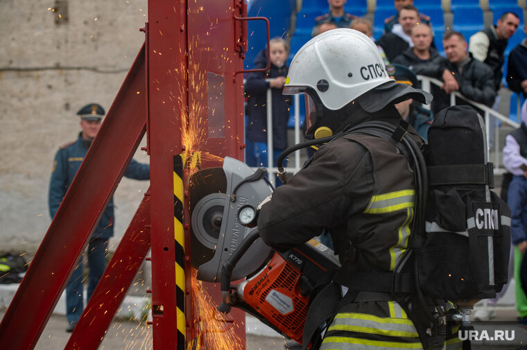    Пожарный распиливает дверь бензорезом Сергей Русанов © URA.RU