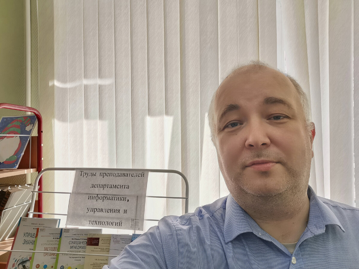 Это я в библиотеке Института цифрового образования МГПУ у стенда с трудами нашего департамента информатики, управления и технологий. Фотография сделана 6 апреля 2023 года.