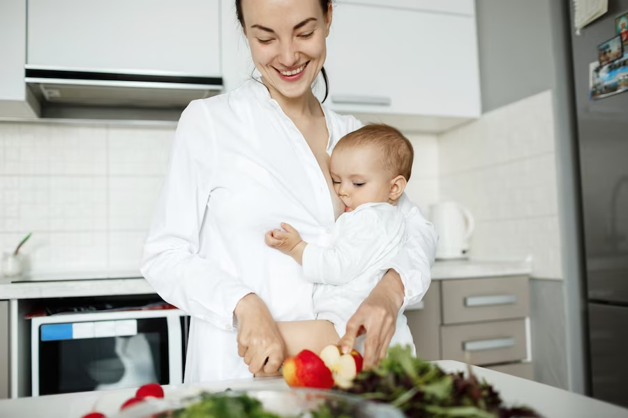 Мать подает. Мама с грудным ребенком на кухне. Мама кормит младенца на кухне. Женщина на кухне кормит детей. Кормление грудью. На кухне.