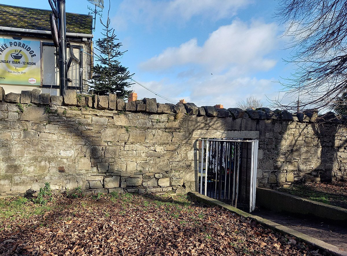 Один из входов в Феникс-парк, напротив паб под названием "Дыра в стене". Laurel Lodged, CC BY-SA 4.0 <https://creativecommons.org/licenses/by-sa/4.0>, via Wikimedia Commons