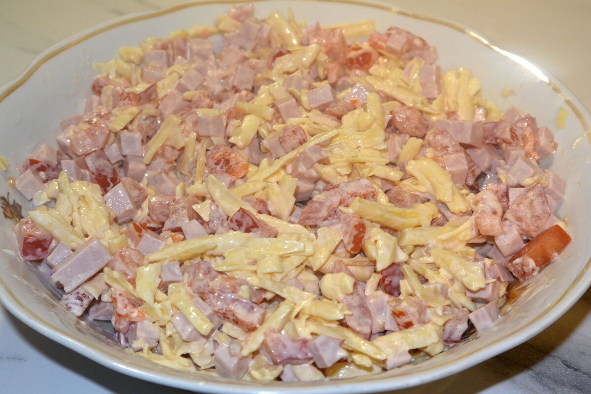 Нарезаем кубиками колбасу, помидоры и сладкий перец. Затем, соединяем вместе колбасу, помидоры, перец, натертый на крупной терке сыр, сливочно-сметанный соус или майонез и всё перемешиваем. 