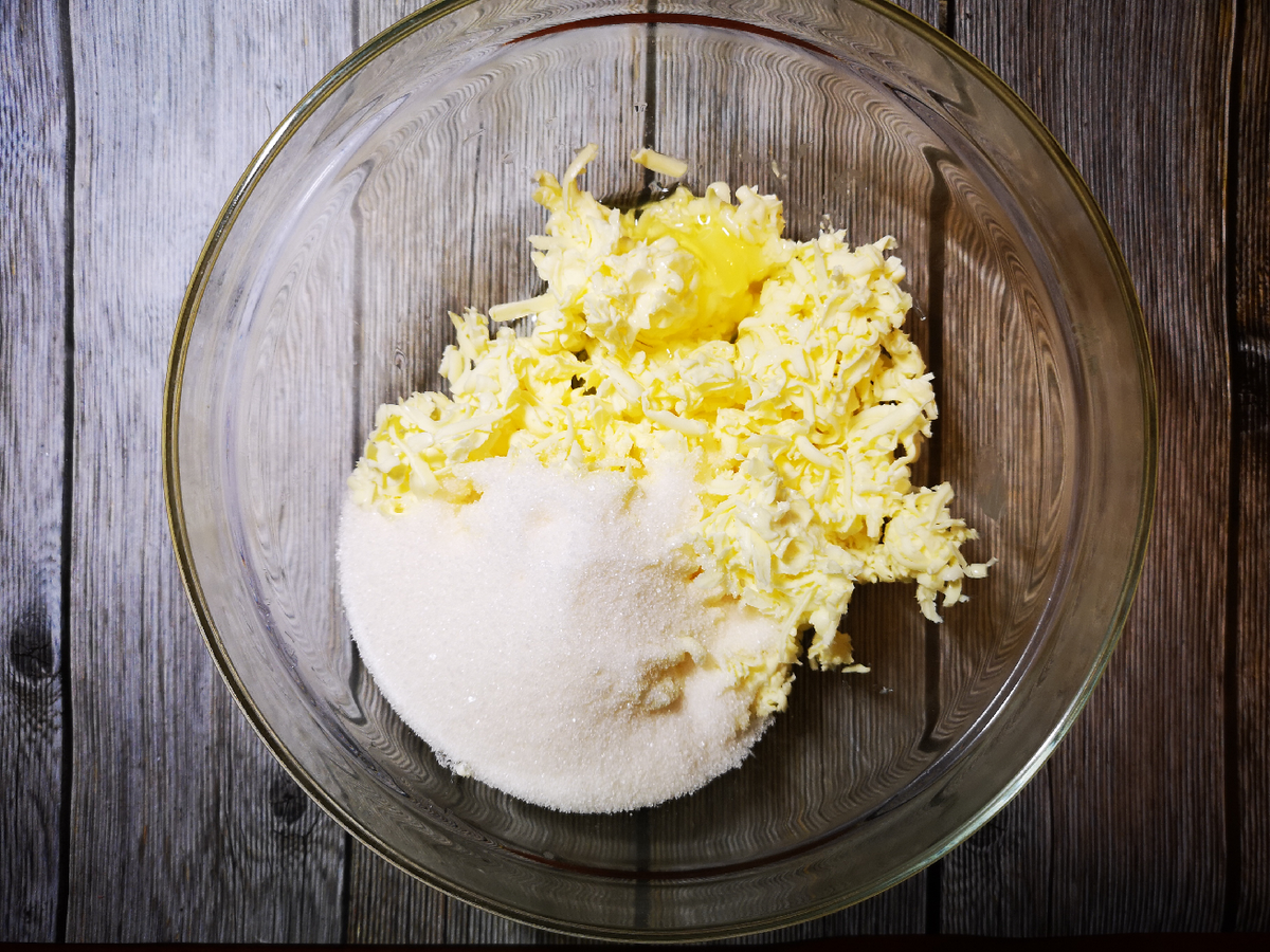  Натираем на крупной тёрке предварительно замороженное сливочное масло, добавляем сахар, яйца...  