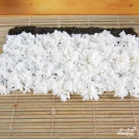 1. Смочить руки и равномерно распределить рис по поверхности листа нори.