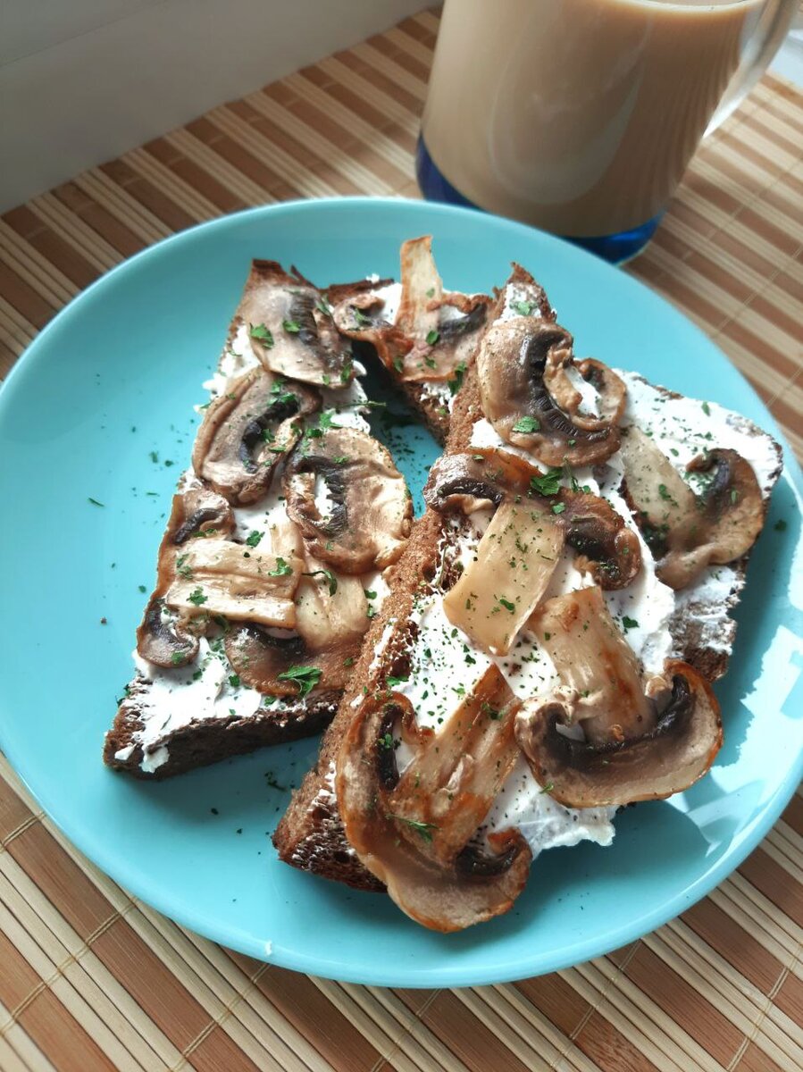 Режем ломтиками грибы и обжариваем на сковороде с каплей масла, немного солим. Хлеб режем и смазываем творожным сыром. Сверху выкладываем грибы и посыпаем молотым чесноком. 