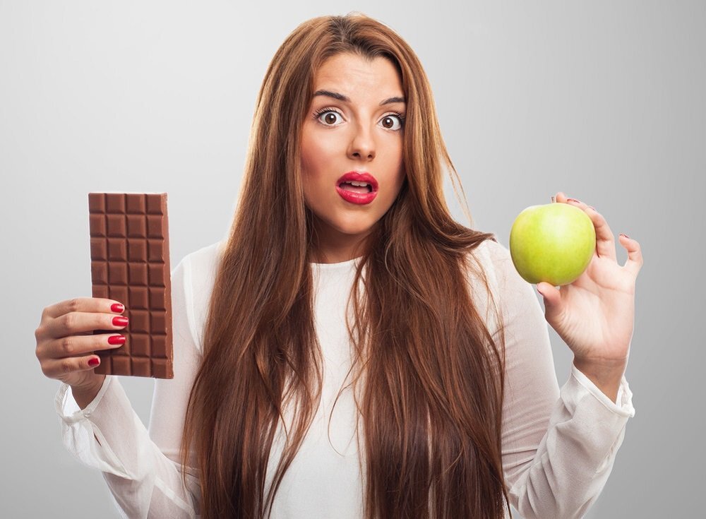 От яблок можно поправиться. Девушка с яблоком. Девушка выбирает. Девушка выбирает шоколад. Шоколад и лишний вес.