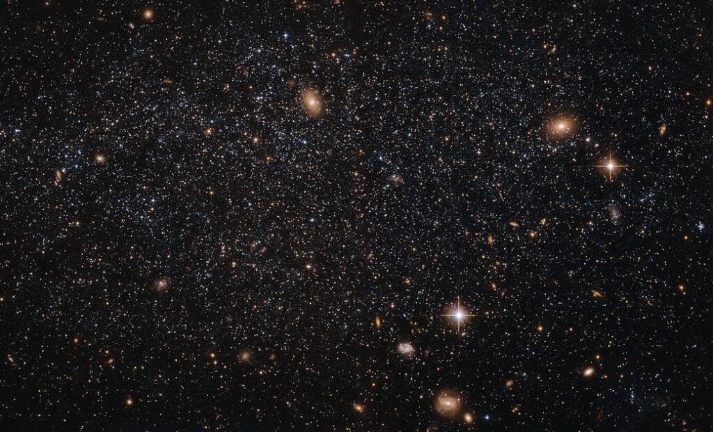    At first glance this NASA/ESA Hubble Space Telescope image seems to show an array of different cosmic objects, but the speckling of stars shown here actually forms a single body — a nearby dwarf galaxy known as Leo A. Its few million stars are so sparsely distributed that some distant background galaxies are visible through it. Leo A itself is at a distance of about 2.5 million light-years from Earth and a member of the Local Group of galaxies; a group that includes the Milky Way and the well-known Andromeda galaxy. Astronomers study dwarf galaxies because they are very numerous and are  simpler in structure than their giant cousins. However, their small size makes them difficult to study at great distances. As a result, the dwarf galaxies of the Local Group are of particular interest, as they are close enough to study in detail. As it turns out, Leo A is a rather unusual galaxy. It is one of the most isolated galaxies in the Local Group, has no obvious structural features beyond being a roughly spherical mass of stars, and shows no evidence for recent interactions with any of its few neighbours. However, the galaxy’s contents are overwhelmingly dominated by relatively young stars, something that would normally be the result of a recent interaction with another galaxy. Around 90% of the stars in Leo A are less than eight billion years old — young in cosmic terms! This raises a number of intriguing questions about why star formation in Leo A did not take place on the “usual” timescale, but instead waited until it was good and ready. Александр Шереметьев