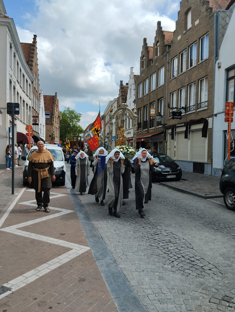 Это не свеча, а святыня из монастыря - в прошлом пункта отправления процессии, куда уже возвращающиеся участники сейчас свернут на боковую улицу, но высоты свеча такой же и ее тоже несут так же женщины - см.статью из википедии в ссылке выше.