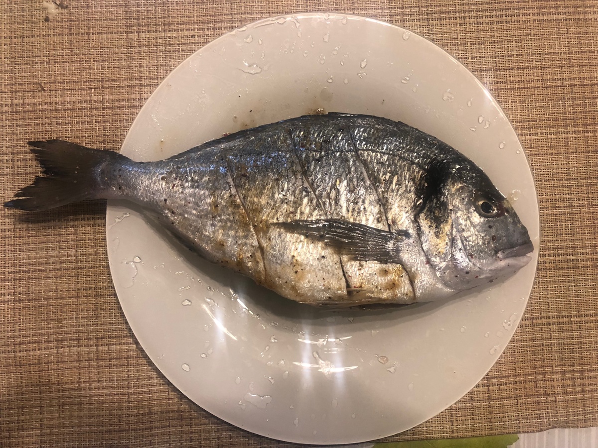  Эта с виду довольно флегматичная рыбина на тарелке называется дорада. Она явно не в настроении - и ее можно понять, через секунду ее нашпигуют лимонами и отправят в духовку. Кому ж это понравится.