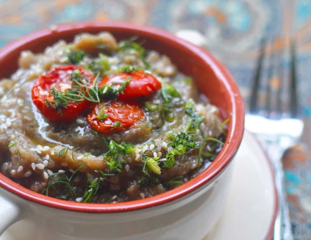 Бабагануш – близкий родственник нашей баклажанной икры, но вкус все же другой: яркий и своеобразный. Пришла к нам эта замечательная закуска с Ближнего Востока, ее особо почитают в Турции и Египте. Бабагануш – это очень нежное и мягкое пюре из баклажанов, щедро сдобренное различными восточными пряностями, тахини, вкус и аромат которых многократно усилен присутствием лимона и чеснока.