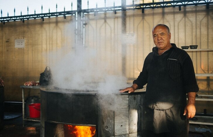 
Хусан-ака - мастер приготовления плова по узбекский или ошпаз – это повар, специализирующийся на приготовлении плова. Плов готовится во дворе на дровах в большом казане, диаметр казанов 1,5 метров. В заведении Центр плова работают 5 поваров, все они мужчины, по традиции женщины не готовят настоящий узбекский плов. Весь Узбекистан разделяется на десять районов, и все они готовят плов по-своему. 
Опыт тут передается от отца к сыну, Хусан готовит плов с 10 лет, с детства отец учил его готовить плов. Сейчас дети Хусана помогают ему и переманивают опыт. 
