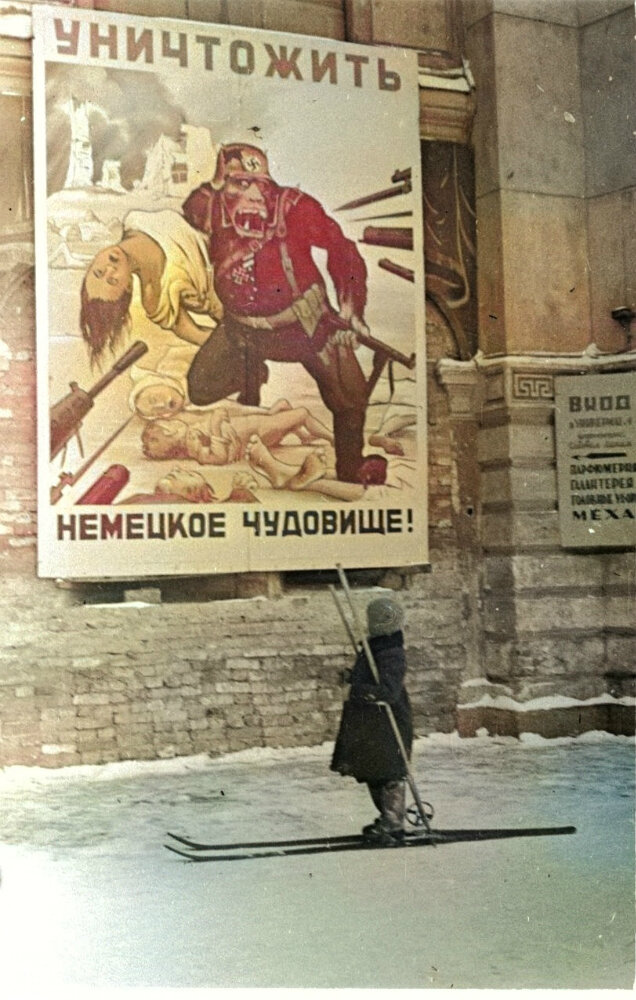 Ребенок на улице блокадного Ленинграда у плаката «Уничтожить немецкое чудовище!». Зима 1941—1942 годов.
