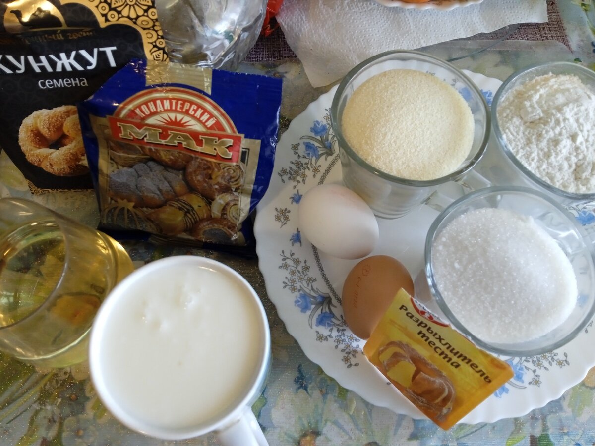 по 200 грамм: муки, манной крупы, кефир и сахарного песка. Кефир чем жирнее, тем вкуснее. Примерно 150 мл. растительного масла, 2 куриных яйца, 1 ч.л. разрыхлителя и....1 ст.ложка семян кунжута, а также 3 ст. ложки кондитерского мака. Кусочек сливочного масла и щепотку панировочных сухарей для формы. Также забыла указать нам понадобится цедра любого цитрусового) У меня мандарин. Вы можете взять лимон, апельсин...лайм)))