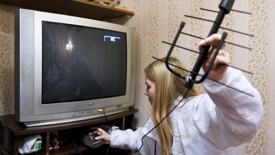 Девушка-волонтер настраивает  работу телевизора с приставкой для цифрового вещания для жителя Твери. Фото: РИА Новости/Валерий Мельников