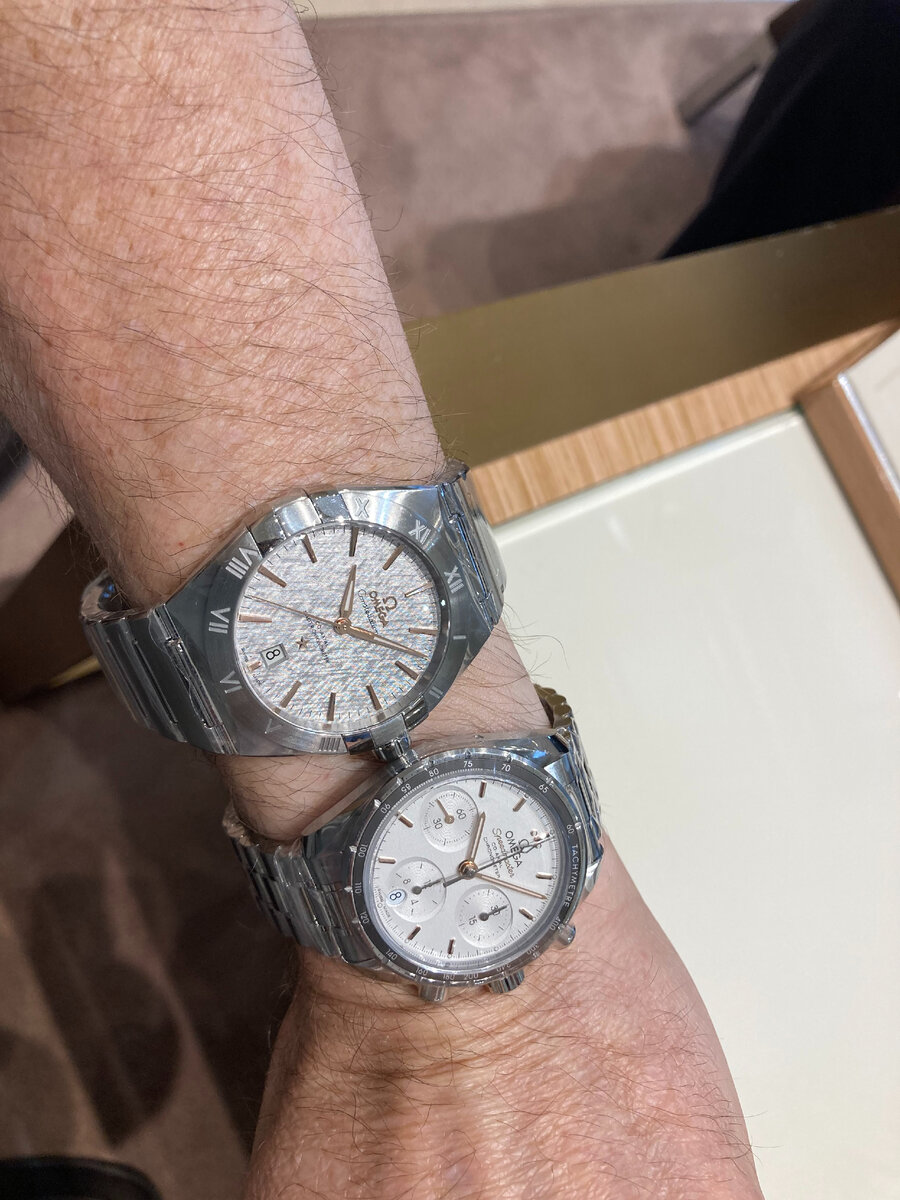 Слева/наверху часы Омега белые Constellation Co‑Axial Master Chronometer 41 mm (диаметр циферблата), а Справа/внизу часы белые Омега Speedmaster 38 Chronographe Co‑Axial Chronometer 38 mm (диаметр циферблата) 