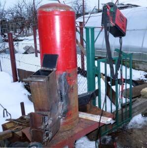 Описываемая печь для обогрева жилища может быть изготовлена из баллона. Первоначально стоит удалить его верхушку, чтобы образовалось отверстие Ø220 мм. Его стоит закрыть, применив металлическую 4-миллиметровую окружность, которая станет выполнять роль варочной поверхности. После этого необходимо сделать рез несколько ниже верхнего шва изделия на 50 мм, это уже практически крышка.