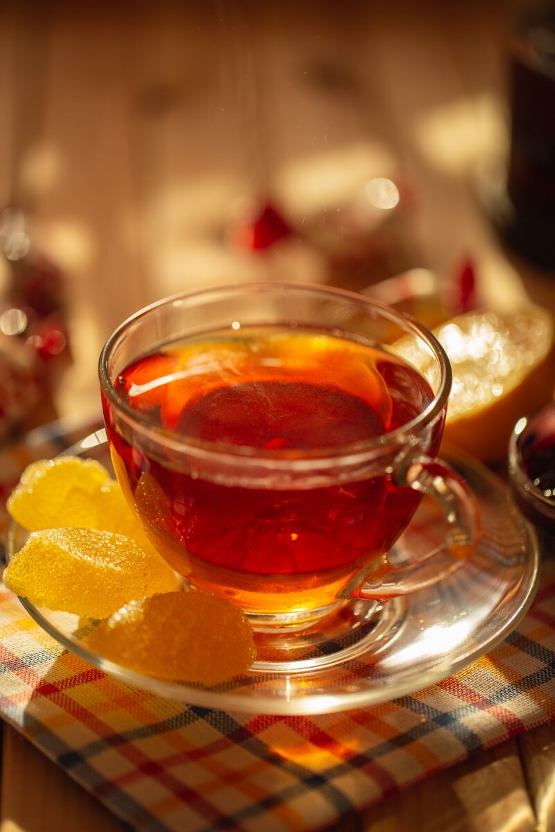 Чашка чая с лимоном на блюдце и мармеладные конфеты