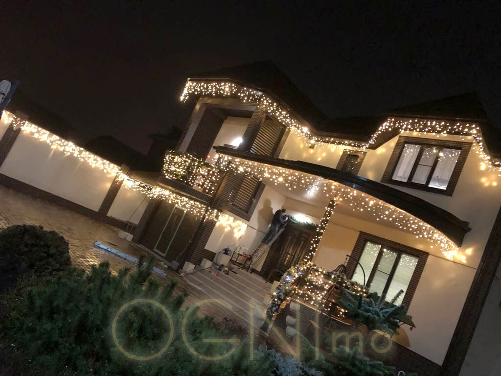 Если добавить к классическим фонарям несколько цветных элементов, декоративных гирлянд или светящихся шнуров, дом еще более преобразится, он будет более декоративным и праздничным. Многое завит и от размера дома, если это небольшой загородный коттедж в 1,5 этажа, то подсветки светодиодной бахромой будет вполне достаточно, чтобы достаточно осветить стены дома и прилегающую территорию. Зачастую в больших домах приходится комбинировать, пересекая световой декор и классику с фасадными фонарями. Хочется отметить, что любая классика также может стать декоративной при условии применения цветных RGB-светильников или интересной комбинации фасадных фонарей и прожекторов. Ведь свет прекрасно подчеркивает форму, структуру, но также может ее полностью переломить и изменить.
