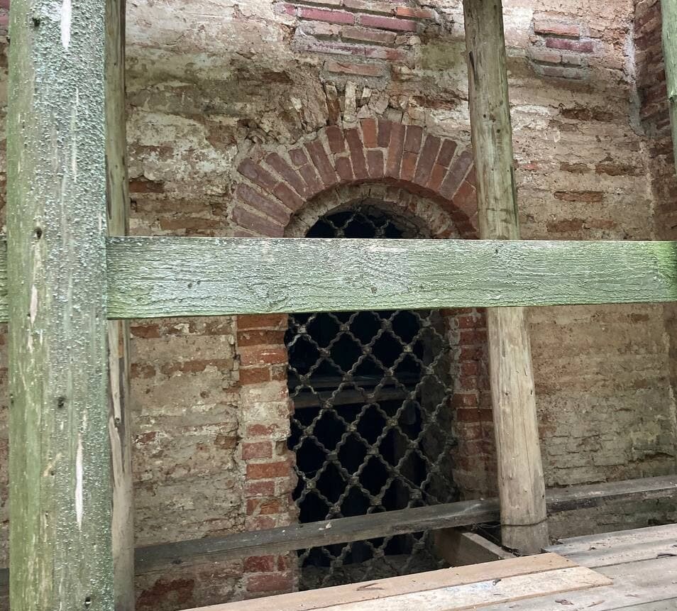 Вверху слева видны остатки окна XII века (свод из тонкого кирпича — плинфы), позже расширенного в XIX веке (современное зарешеченное)