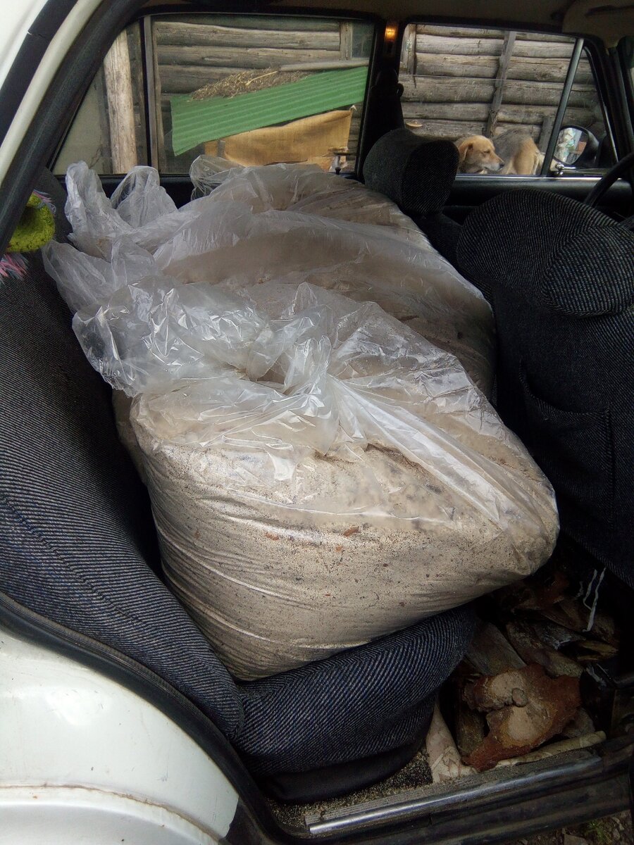 На заднем сиденье поместилось несколько мешков, уже выгружаются