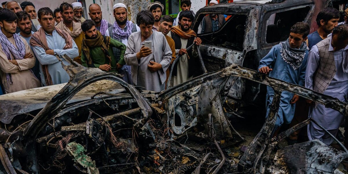 Relatives and neighbors of the Ahmadi family gathered around the incinerated husk of a vehicle targeted and hit 
