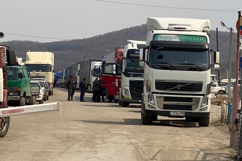 Перевозчики сообщают, что ситуация на погранпереходах с Китаем не изменилась за последние две недели, люди живут и ночуют в машинах.  
По мнению предпринимателей, в этой ситуации виноват не только карантин, но также отсутствие договоренностей российской и китайской стороны и давние проблемы инфраструктуры, до сих пор являющейся частной собственностью.

"В понедельник 27 апреля на Пограничном сохраняется очередь из 200-250 машин. Забиты все стоянки, все тупики. Люди живут здесь уже по две недели", — рассказал один из очевидцев.

Китайские власти приняли жесткие меры на пунктах пропуска после повторной вспышки коронавируса в приграничной с Приморьем провинции Хэйлунцзян. Китайская сторона сократила грузопоток, проводится тщательный осмотр и дезинфекция машин, проверка документов и состояния самих водителей. Водителям большегрузов теперь запрещено ночевать в Китае, они обязаны доставить груз и вернуться назад. Правительство края ведет переговоры о возобновлении грузового сообщения в полном объеме.

"Пропускают максимум 15-20 машин в день. Причем ситуация на погранпереходах отличается незначительно, очереди сохраняются везде. Вся провинция Хэйлунцзян под карантином", — прокомментировал директор компании "АгроФреш" Сергей Юрченко.

Представители логистических компаний сообщают, что ограничения повлияли на сроки доставки грузов. Клиенты, чьи заказы уже в пути, вынуждены ждать. Если отправки еще не было, некоторые выбирают авиаперевозку. Также возможна альтернатива доставки грузов по морю до порта Владивосток, а оттуда в случае необходимости — самолетом до Москвы.

"Тем не менее, надо понимать, что не весь груз можно отправить морем. Это хорошая альтернатива для непродовольственных товаров или товаров с длительным сроком годности, но не для скоропорта. Если говорить о железной дороге, далеко не у всех заключены договоры на поставки в вагонах. Автотранспорт как был, так и остается незаменимым для многих компаний", — рассказал Сергей Юрченко.

Участники рынка считают, что разрешить ситуацию помогли бы договоренности с китайской стороной, в том числе о безопасной системе перевозок.

"Механизмы можно придумывать разные — транзиты, пересадки. Все это возможно — обеспечить условия, чтобы в Китай не попадали зараженные водители. Просто никто не хочет этим заниматься, ведь от очередей не зависят доходы правительства", 
— прокомментировал один из перевозчиков.

Как вариант, он предлагает систему тройного контроля. Водитель, который занимается перевозками на российской территории, оставляет машину на пункте пропуска. Там есть свои водители, которые перегоняют фуру в Китай, и уже китайский водитель едет на загрузку. Далее — в обратном порядке. Карантинные меры при этом обязательны.

Как отмечает глава профсоюза "Транспортных перевозчиков Приморского края" Петр Куприянов, ситуация на самом деле не нова. По его оценке, своевременно решать возникающие проблемы и в целом повысить эффективность пропускной системы мешает коммерческая принадлежность погранпереходов.

"В связи с коронавирусом грузооборот серьезно сократился. Некоторые предприятия не работают. Однако проблема стоит очень остро, и на самом деле она возникла не сегодня и не вчера. Заниматься погранпереходами нужно было давно", — говорит собеседник редакции.

В регионе деятельности Дальневосточного таможенного управления расположено 63 пункта пропуска, 

на российско-китайском участке государственной границы России в ДФО функционирует 15 погранпереходов. Но инфраструктура большинства из них находится в собственности коммерческих организаций, которые не заинтересованы в обустройстве и оснащении погранпереходов.
О том, что право собственности на погранпереходы в ДФО будут постепенно переводить из частной в государственную, заявлял ранее и полпред Юрий Трутнев, назвавший происходящее безобразием.

"Погранпереходы нужно перестраивать, увеличивать пропускную способность с российской стороны, работать эффективнее. А с китайской можно договориться. То, что это до сих пор частная собственность, противоречит законодательству, о чем говорил и президент", — сказал Петр Куприянов, добавив, что начальник транспорта города Суйфыньхэ разделяет негативную оценку Юрия Трутнева.

Напомним, проблема очередей на российско-китайской границе возникла 24 января. Китайская сторона закрыла пропускные пункты на границе с Россией. Потом сообщение возобновилось, но провинция Хэйлундзян ввела новые ограничения, чтобы обеспечить централизованную проверку и карантин возросшего грузопотока.