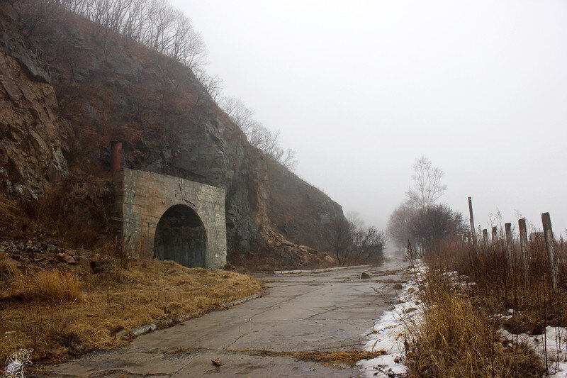  У подножия скалы КП выдаёт здоровенный входной портал, когда-то затянутый маскировочной сетью, а во время учений сеть и вовсе натягивалась над прилегающей площадкой и дорогой, цепляясь за столбы у периметра.