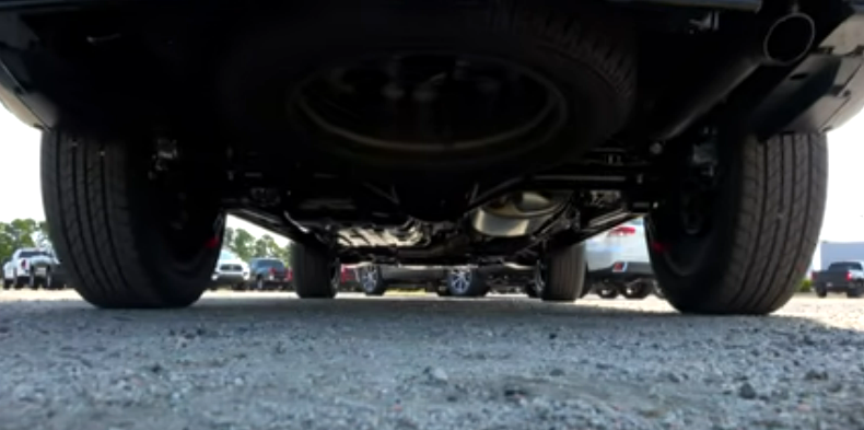 Запаска подвешена под багажным отделением снаружи.