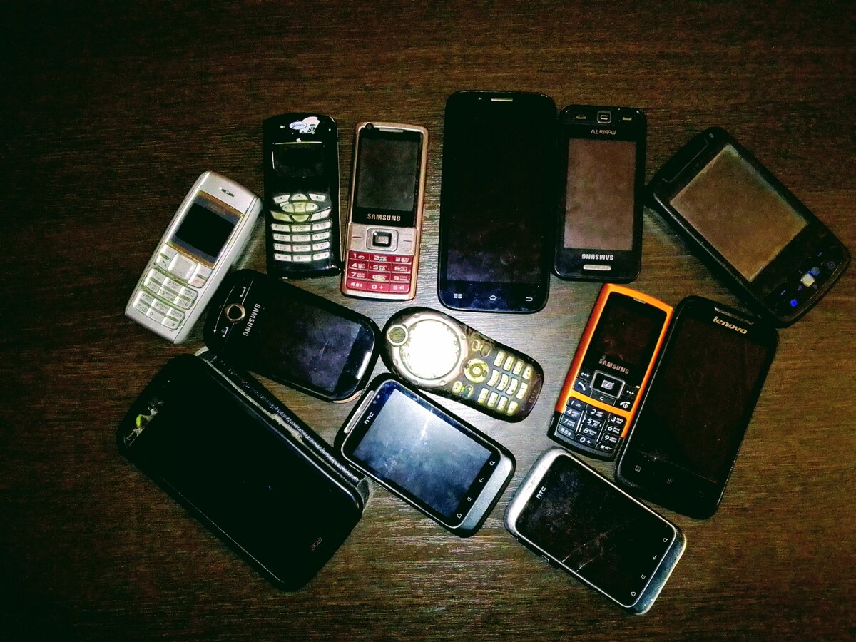 Сдать разбитый телефон. Старые смартфоны. Много разбитых телефонов. Старый сломанный смартфон. Куча старых смартфонов.
