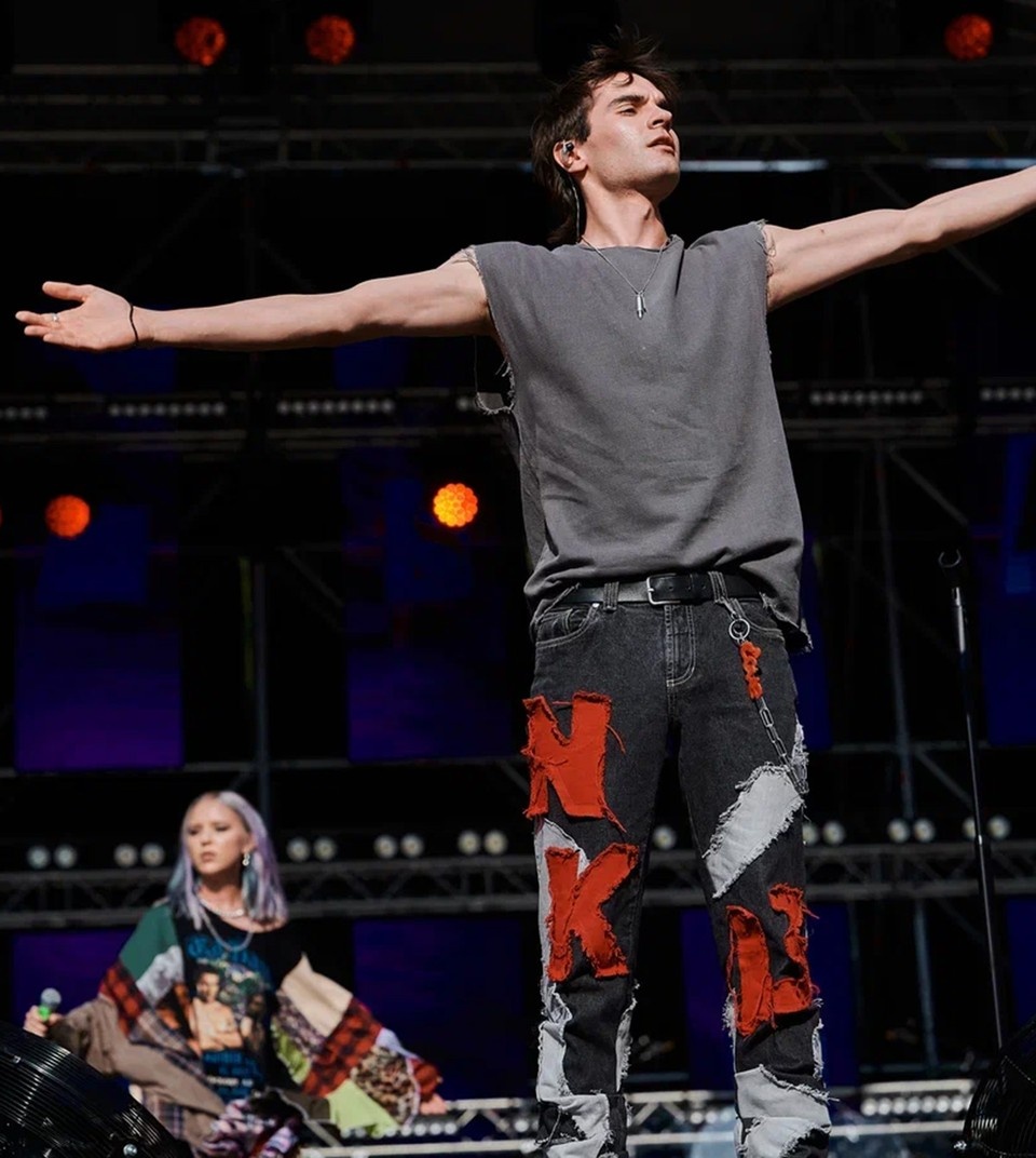     Никита Киоссе вышел в образе молодого Константина Кинчева-серая футболка без рукавов и джинсы с объёмными цветными аппликациями.