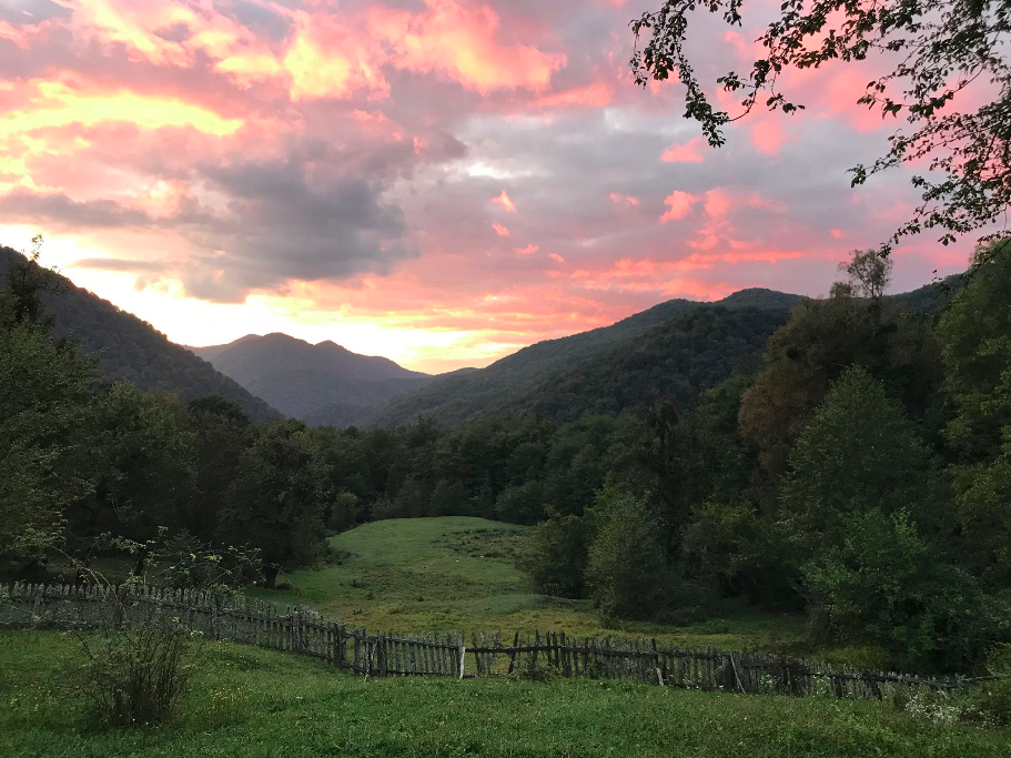 Этот закат мы встретили в той самой избе, что одиноко стоит в горах Сочинского нацпарка. Добраться сюда можно только пешком. Для баланса, видимо, для контраста с красивым видом, периодически кто-то здесь кого-то ест: например, шакалы недавно сожрали кота-добряка, а волки иногда выманивают с людской территории местных собак - ну и, понятно, сжирают. «Волки тощие, худые, на людей никогда не нападут», - обьясняет Иван, который живет в этой горной избе три года, а по вечерам включает генератор, тот, в свою очередь, питает электричеством усилитель сотового сигнала - тогда в одной из комнат можно сделать звонок. В Москву приехали - здесь совершенно другие темы для бесед: сеть ловит, где пожелаешь, про шакалов ни слова, кто-то ушел по тропе в барбершоп, другие отправились вверх по реке и смотрят нового Вдудя.