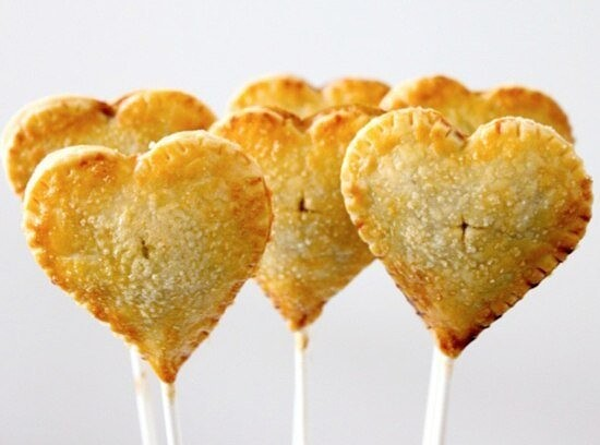 Ингредиенты:  
ТЕСТО 
- 350 гр муки 
- 230 гр сливочного масла 
- 60-120 мл холодной воды 
- 5 ст.л. сахара 
- 1/4 ч.л. соли 
НАЧИНКА 
- густое повидло или любые ягоды 
- яичный желток 
- 1 ч.л. молока 

Приготовление: 
1. Муку, соль и сахар перемешайте. Добавьте масло и снова хорошо перемешайте, пока смесь не будет напоминать грубую хлебную крошку. 
2. Влейте медленно 1/4 стакана воды. Тесто должно склеиваться в руках. При необходимости добавьте еще воды. Перемешайте еще полминуты. Тесто положите в миску, закройте пищевой пленкой и поставьте в холодильник примерно на 20 мин. 
3. Тесто выложите на раскаточную доску, посыпанную мукой, и тонко раскатайте ~3-5 мм. 
4. Формочкой для нарезки печенья вырезайте сердечки. 
5. Противень застелите бумагой для запекания. Готовые сердечки теста положите на противень и не глубоко воткните деревянную шпажку. 
6. Положите начинку. Закройте вторым кружком теста. Скрепите 2 кружка, так чтобы начинка не вытекла 
7. Готовый пирожок смажьте яичным желтком. Сделайте 3 отверстия на верхней стороне пирожка острым ножом или вилкой. 
8. Выпекайте в нагретой духовке до 175 градусов 20-25 мин.