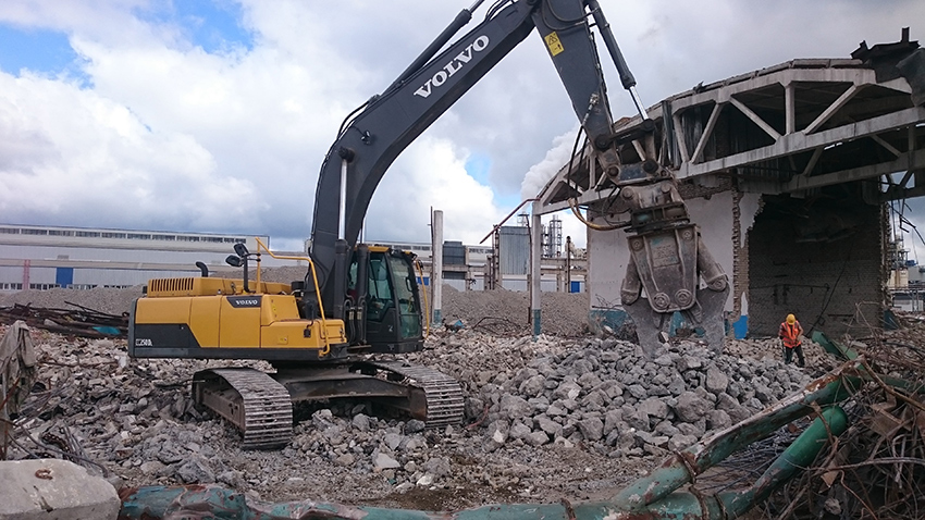 Гусеничный экскаватор с гидроножницами демонтирует здание