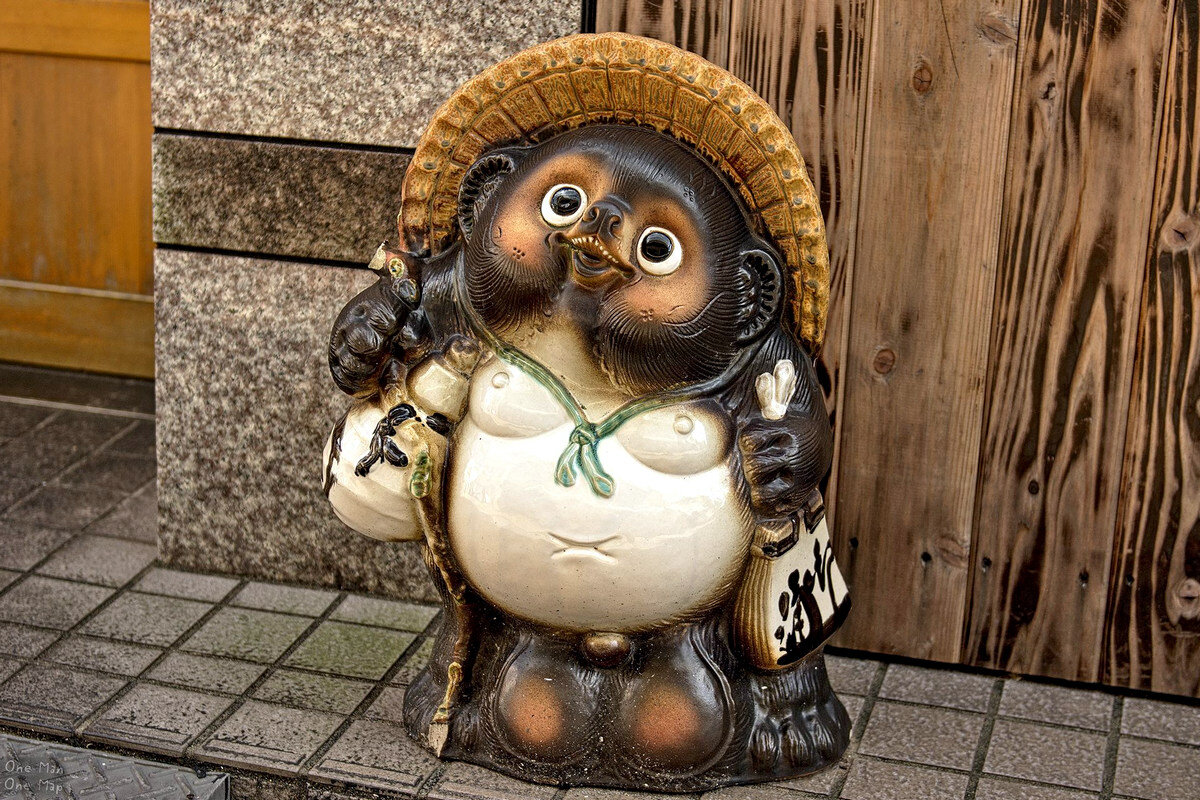 Лучшее тануки. Статуя Тануки в Японии. Японская енотовидная собака Тануки. Японские фигурки Тануки. Тануки персонаж.