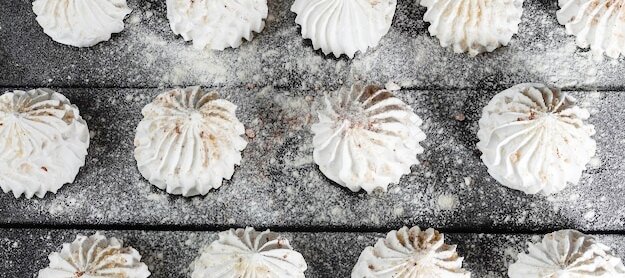 Натюрморт в стиле еды кулинарный фон с безе на темном деревянном фоне. Freepick.com