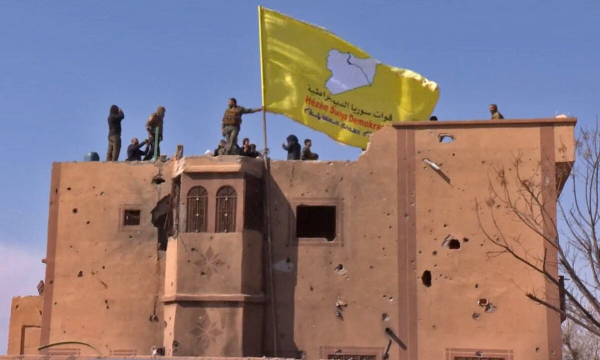 Поддерживаемые США бойцы Сирийских Демократических сил (SDF) поднимают флаг над зданием в Багузе