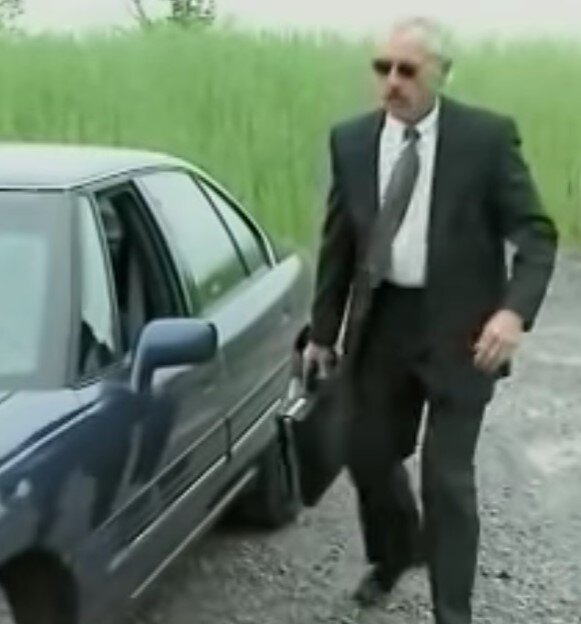 Респектабельный бизнесмен выходит из авто с респектабельным кейсом в руке.