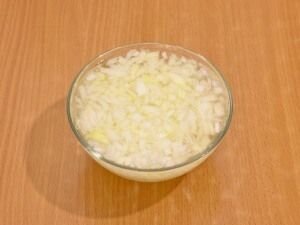    Куриное филе нужно хорошо промыть под проточной водой, затем переместить в кастрюлю и залить водой, чтоб она полностью покрывала филе, добавить щепотку соли и поставить кастрюлю на сильный огонь. Когда вода закипит, огонь убавьте и варите курочку до состояния полной готовности. Затем выньте ее из воды и остудите, нарежьте на мелкие кубики.     Лук очистите от шелухи и ополосните под водой, затем мелко нарежьте и пересыпьте в глубокую мисочку. Заранее вскипяченной и слегка остуженной водой, залейте лук. После этого лучок в салате не будет горчить. Слейте воду с лука и хорошенечко промойте его под холодной проточной водой.  